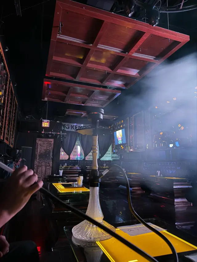 Guest reaching for the hose at a hookah on a lounge table