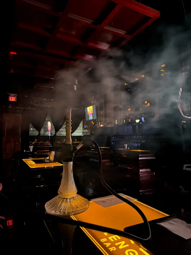 Hookah on a dark lounge table, hose coiled beside it
