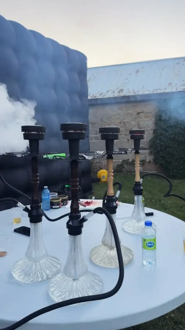 Hookahs on a white garden table at dusk, smoke drifting off the bowls