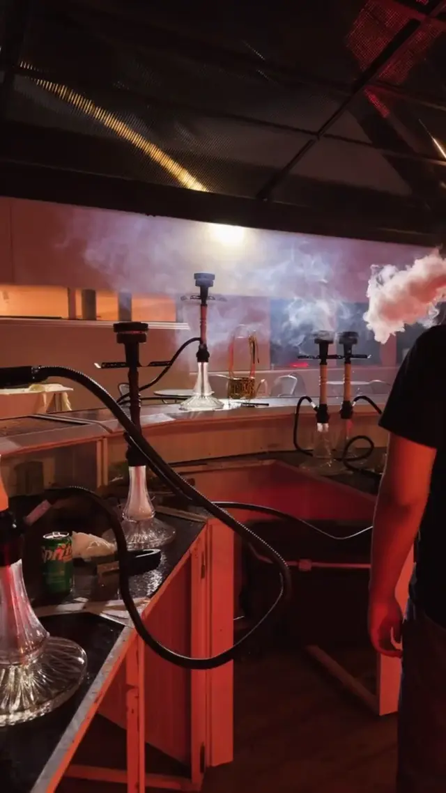 Hookah on the bar of a red-lit venue, smoke across the counter