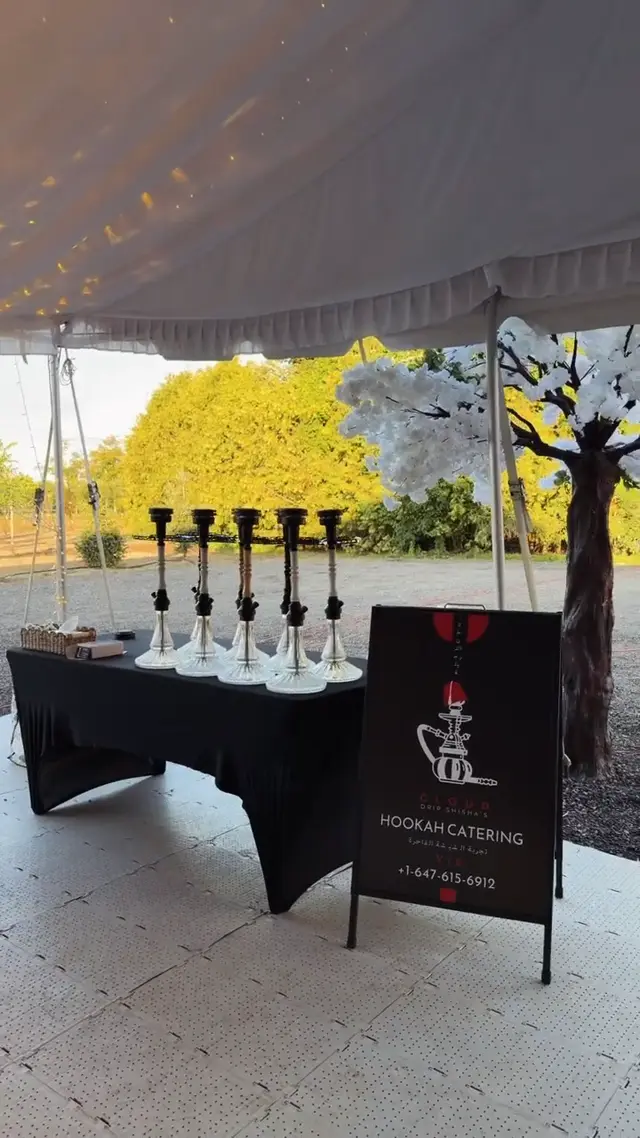 Row of hookahs on a draped table under a garden marquee