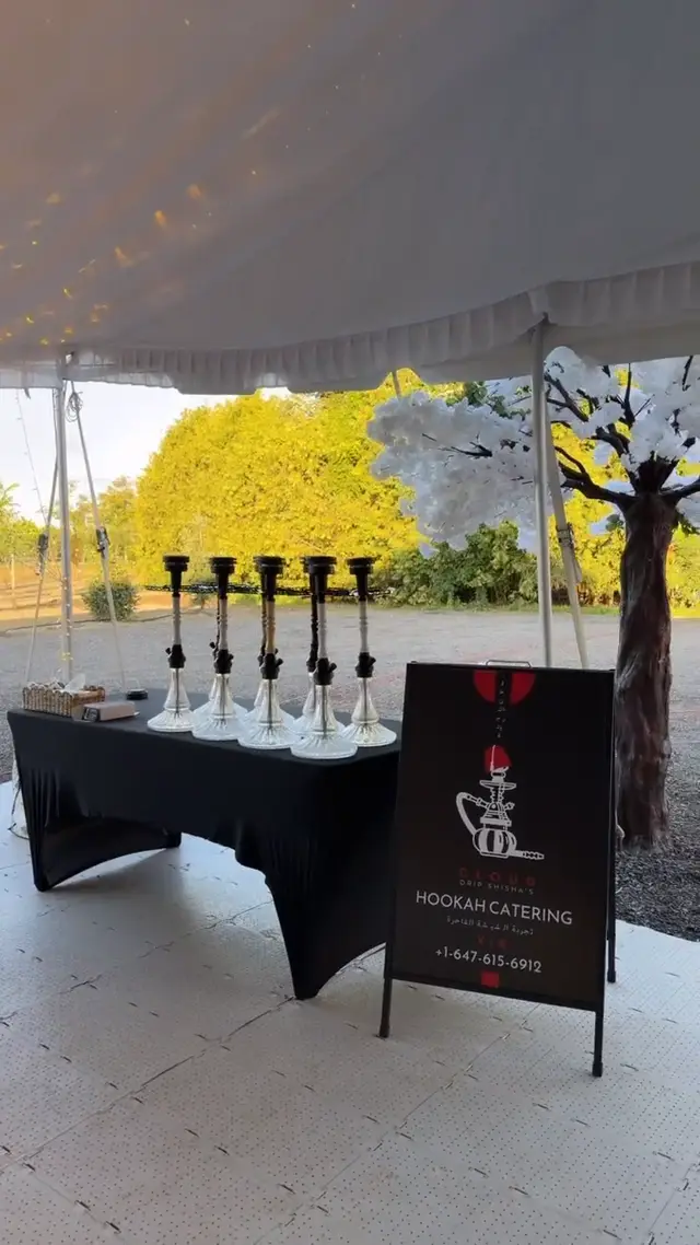 Row of hookahs on a draped table under a garden marquee