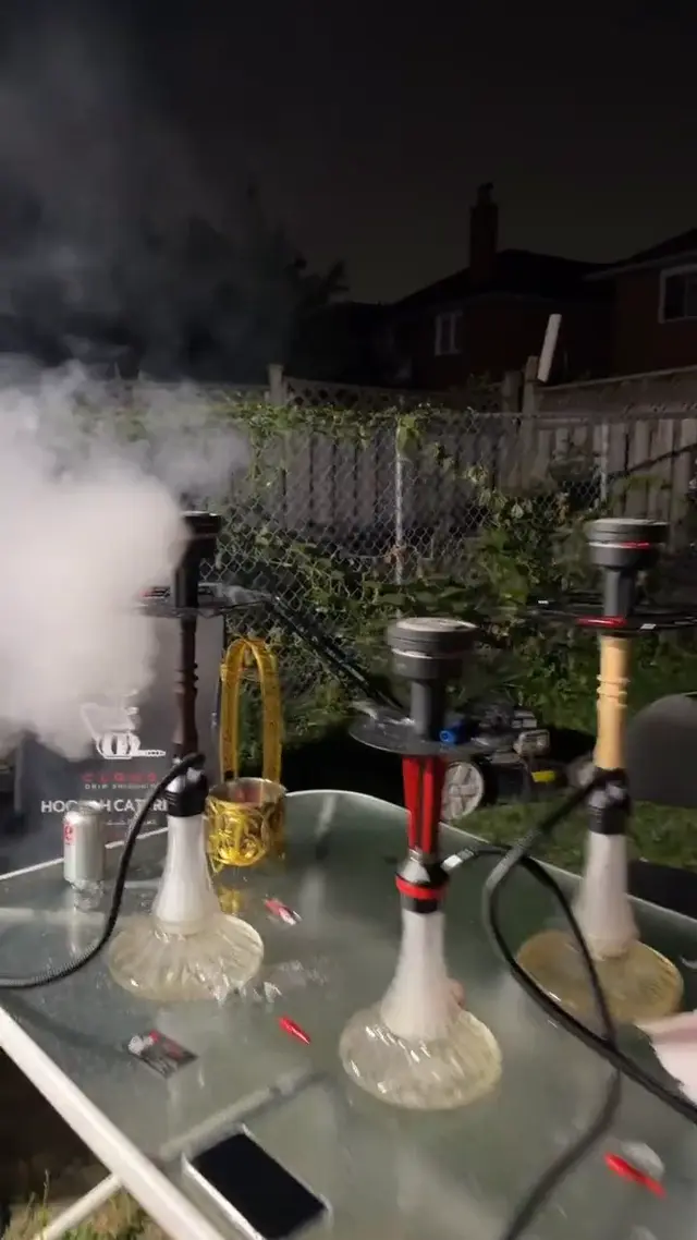 Hookahs on a glass garden table, smoke drifting across the lawn